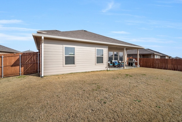 rear view of property featuring a yard and a patio area