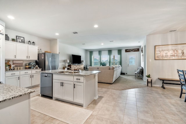 kitchen featuring sink, light stone counters, stainless steel appliances, a kitchen island with sink, and white cabinets