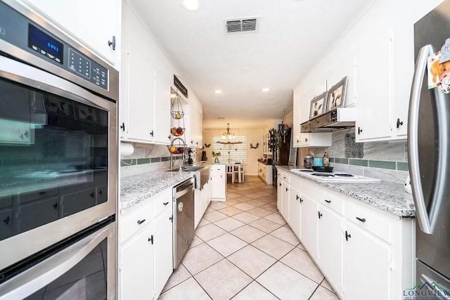 kitchen featuring stainless steel appliances, white cabinets, and decorative backsplash