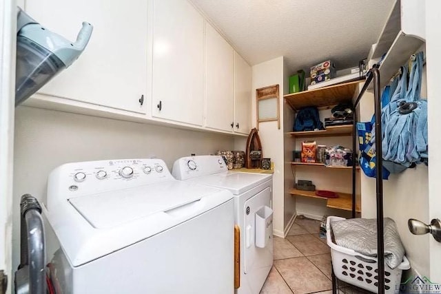 washroom with cabinets, washing machine and dryer, light tile patterned floors, and a textured ceiling