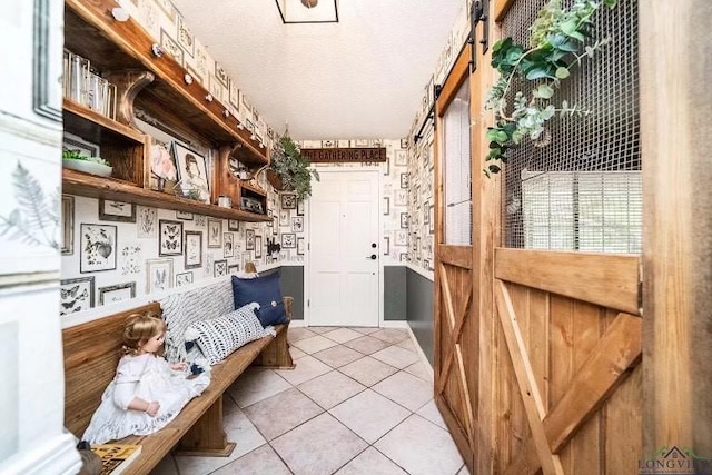 mudroom with a barn door and light tile patterned floors