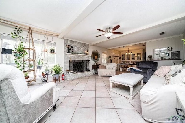 tiled living room featuring beamed ceiling, a fireplace, and ceiling fan with notable chandelier