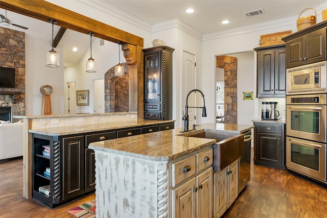 kitchen featuring appliances with stainless steel finishes, dark hardwood / wood-style floors, a center island with sink, and dark brown cabinetry