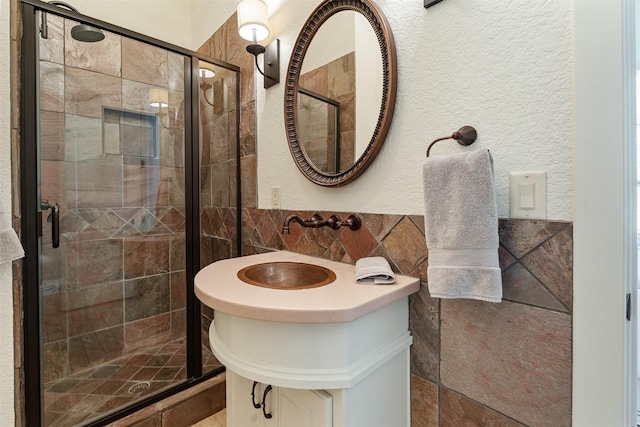 bathroom featuring tile walls, vanity, and a shower with shower door