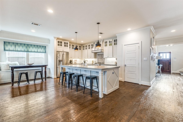 kitchen with premium range hood, high end fridge, an island with sink, dark hardwood / wood-style flooring, and decorative light fixtures