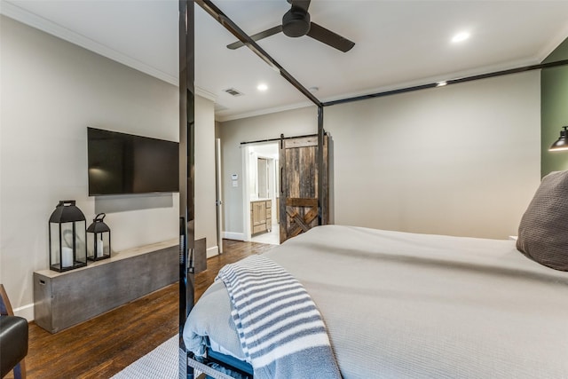 bedroom featuring crown molding, a barn door, dark hardwood / wood-style flooring, and ensuite bath