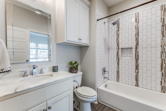 full bathroom with hardwood / wood-style floors, vanity, tiled shower / bath, and toilet