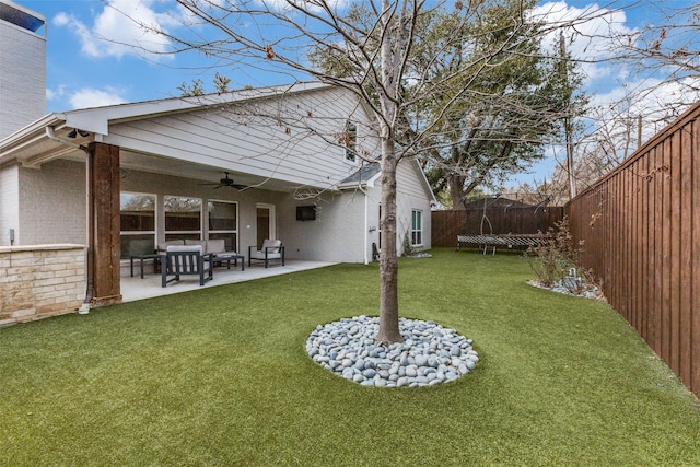 view of yard featuring a trampoline, ceiling fan, and a patio area