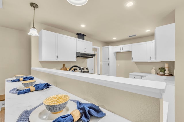 kitchen with white cabinetry, decorative light fixtures, and kitchen peninsula