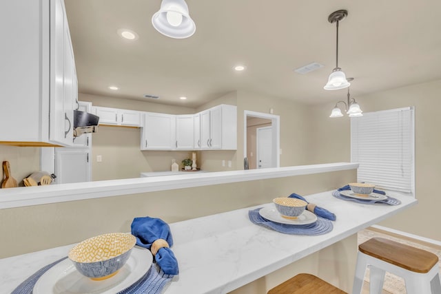 kitchen featuring white cabinetry, hanging light fixtures, a kitchen breakfast bar, a notable chandelier, and breakfast area