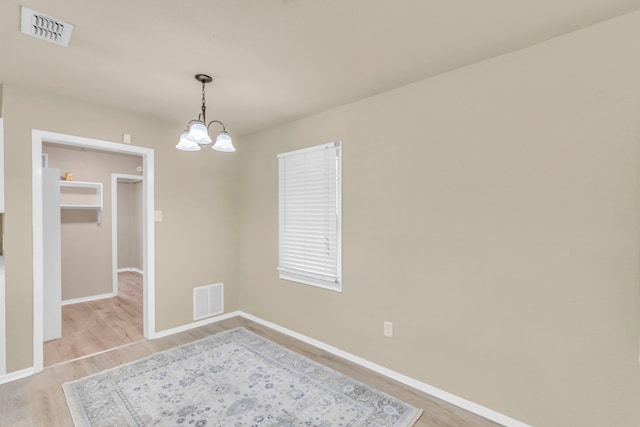 unfurnished room with an inviting chandelier and light wood-type flooring