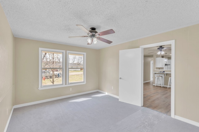 carpeted spare room with ceiling fan, ornamental molding, and a textured ceiling