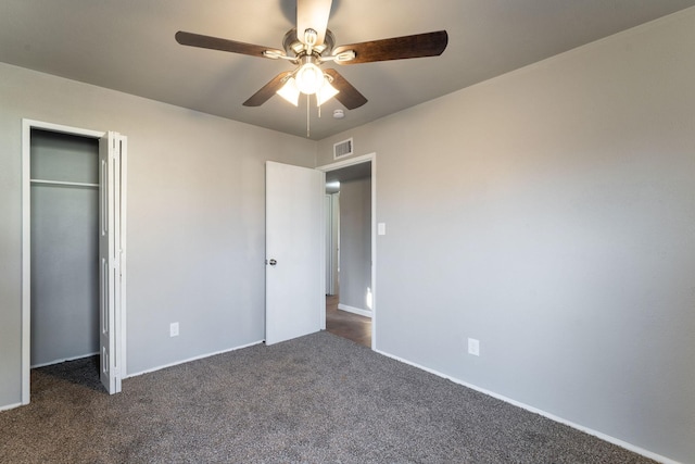 unfurnished bedroom with dark colored carpet, ceiling fan, and a closet