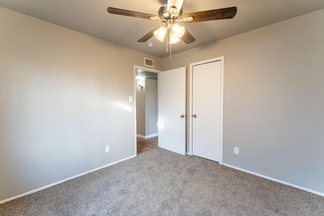 unfurnished bedroom with dark colored carpet, ceiling fan, and a closet