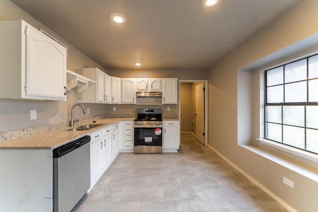 kitchen featuring white cabinetry, stainless steel appliances, light stone countertops, and sink