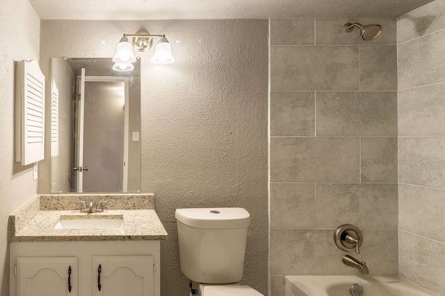 full bathroom featuring tiled shower / bath, vanity, a textured ceiling, and toilet