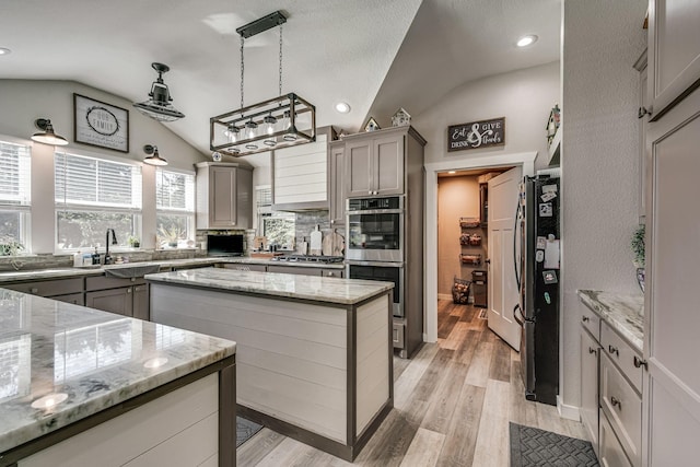 kitchen featuring lofted ceiling, decorative light fixtures, gray cabinets, and appliances with stainless steel finishes