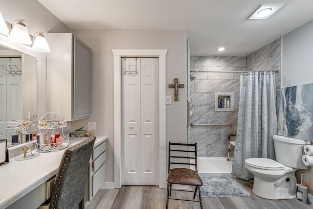 bathroom with hardwood / wood-style flooring, vanity, toilet, and walk in shower