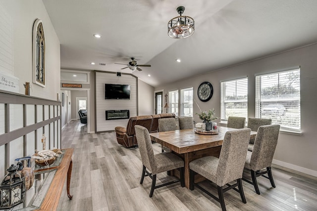 dining area with lofted ceiling, a fireplace, ceiling fan, and light hardwood / wood-style flooring