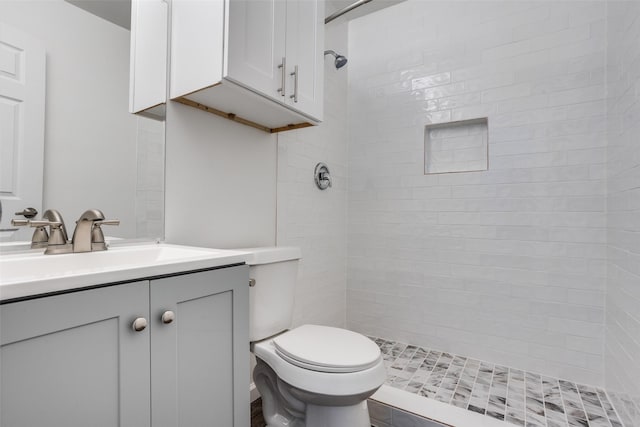 bathroom with vanity, toilet, and a tile shower