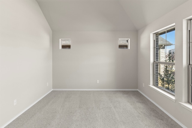 carpeted empty room featuring vaulted ceiling