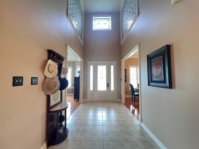 foyer entrance featuring light tile patterned flooring, plenty of natural light, and a high ceiling