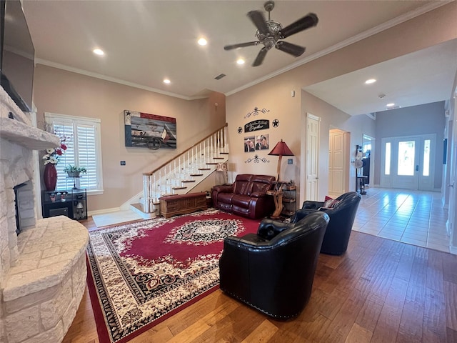 living room with ceiling fan, ornamental molding, a fireplace, and hardwood / wood-style floors