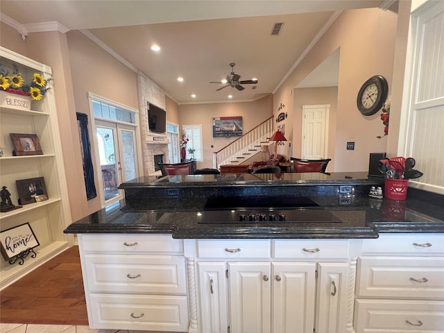 kitchen with white cabinetry, ornamental molding, and dark stone counters