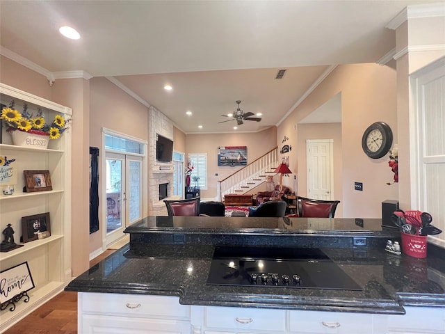 kitchen featuring dark stone countertops, hardwood / wood-style flooring, ornamental molding, and white cabinets