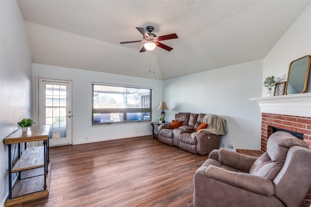 living room featuring ceiling fan, lofted ceiling, dark hardwood / wood-style floors, and a brick fireplace