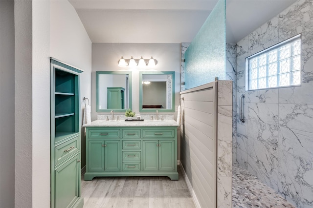 bathroom with tiled shower, wood-type flooring, and vanity