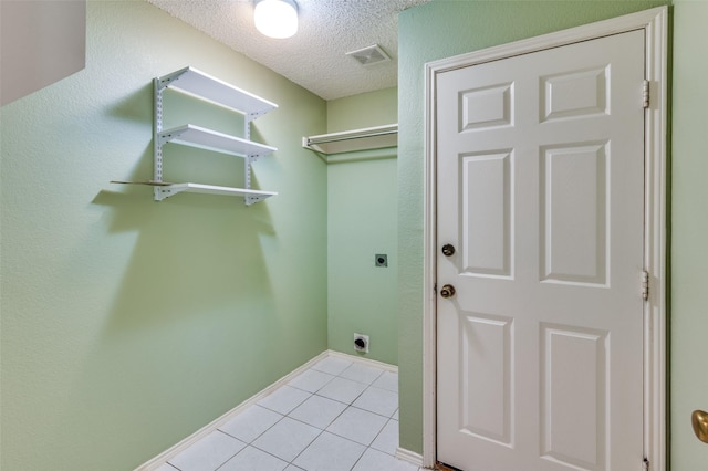 laundry area featuring light tile patterned flooring, electric dryer hookup, and a textured ceiling