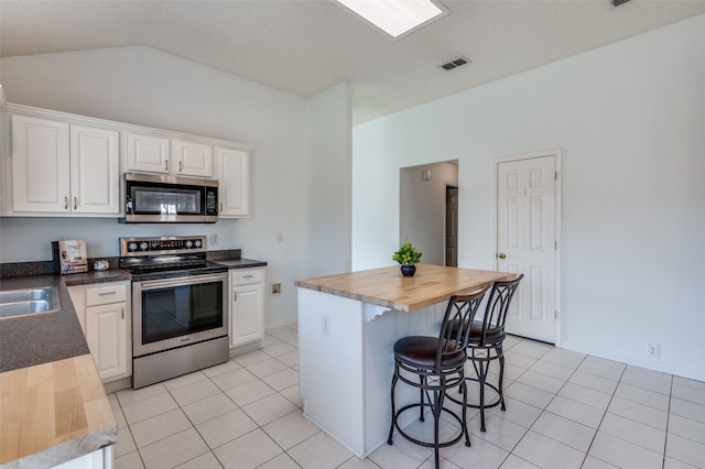 kitchen featuring light tile patterned floors, stainless steel appliances, a center island, and white cabinets