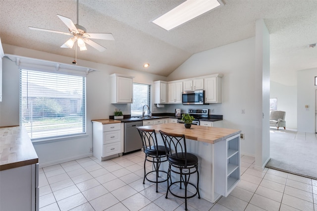 kitchen featuring white cabinetry, wooden counters, stainless steel appliances, and sink