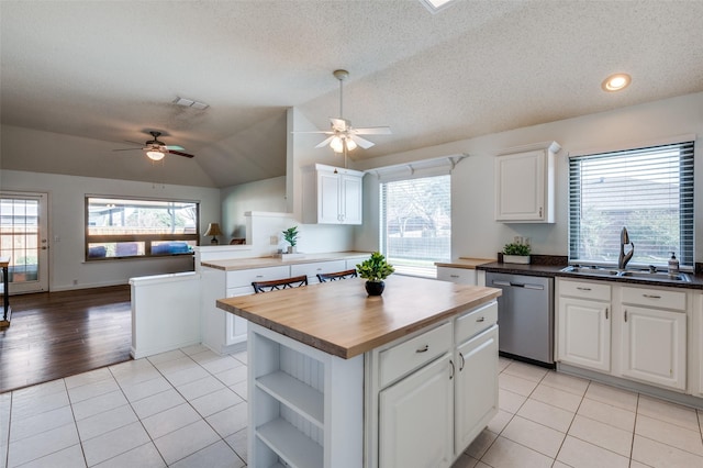 kitchen with sink, dishwasher, butcher block counters, a center island, and white cabinets