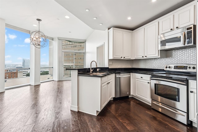 kitchen featuring sink, white cabinetry, hanging light fixtures, appliances with stainless steel finishes, and kitchen peninsula