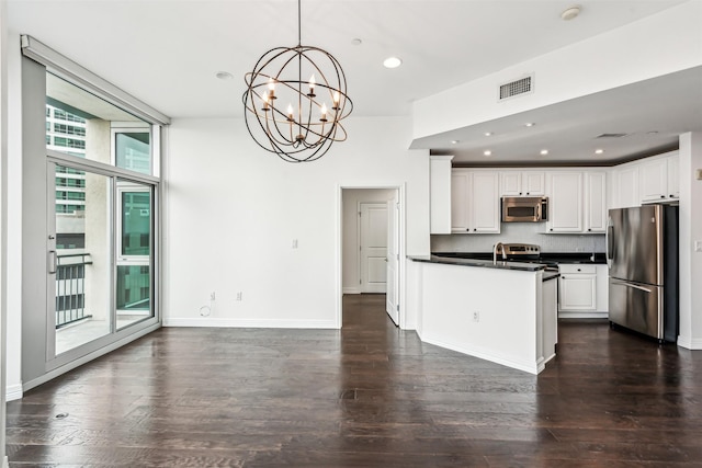 kitchen featuring appliances with stainless steel finishes, hanging light fixtures, tasteful backsplash, white cabinets, and dark hardwood / wood-style flooring