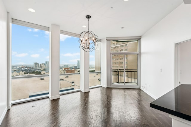 unfurnished dining area featuring dark wood-type flooring, a notable chandelier, and a wall of windows