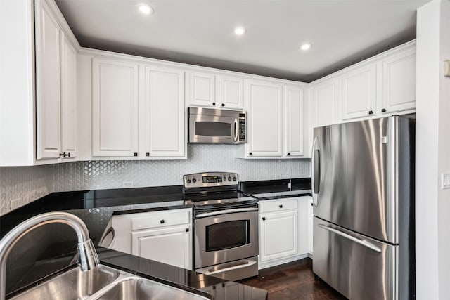 kitchen with stainless steel appliances, white cabinetry, sink, and dark wood-type flooring