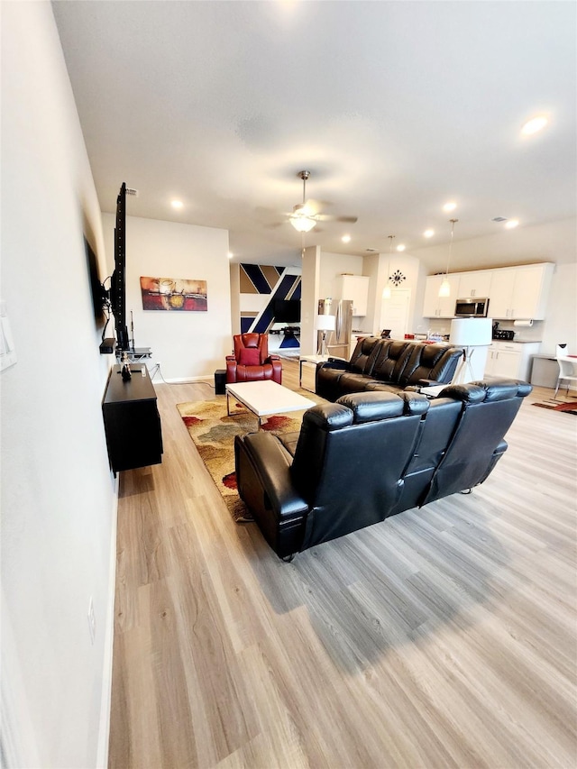 living room with light hardwood / wood-style floors and ceiling fan