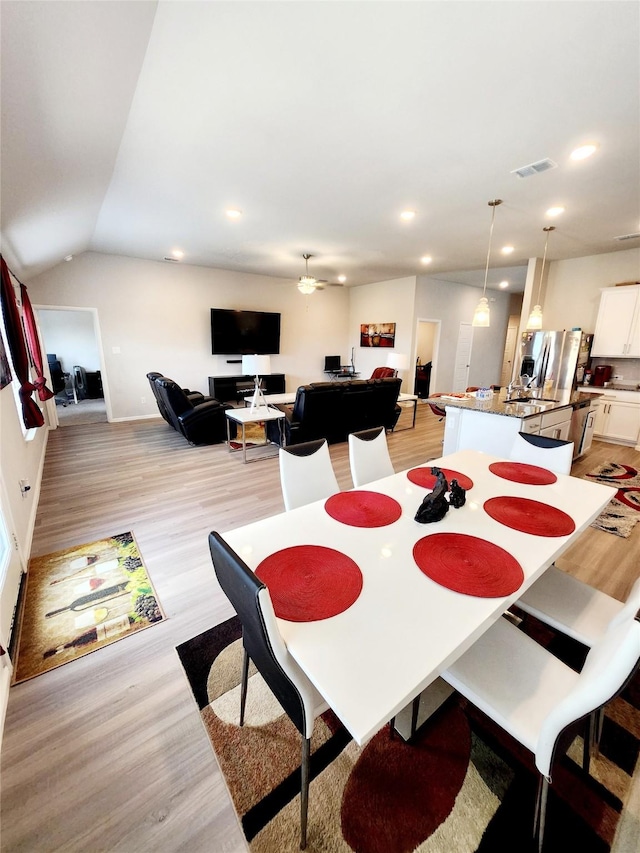 dining area featuring lofted ceiling and light hardwood / wood-style flooring