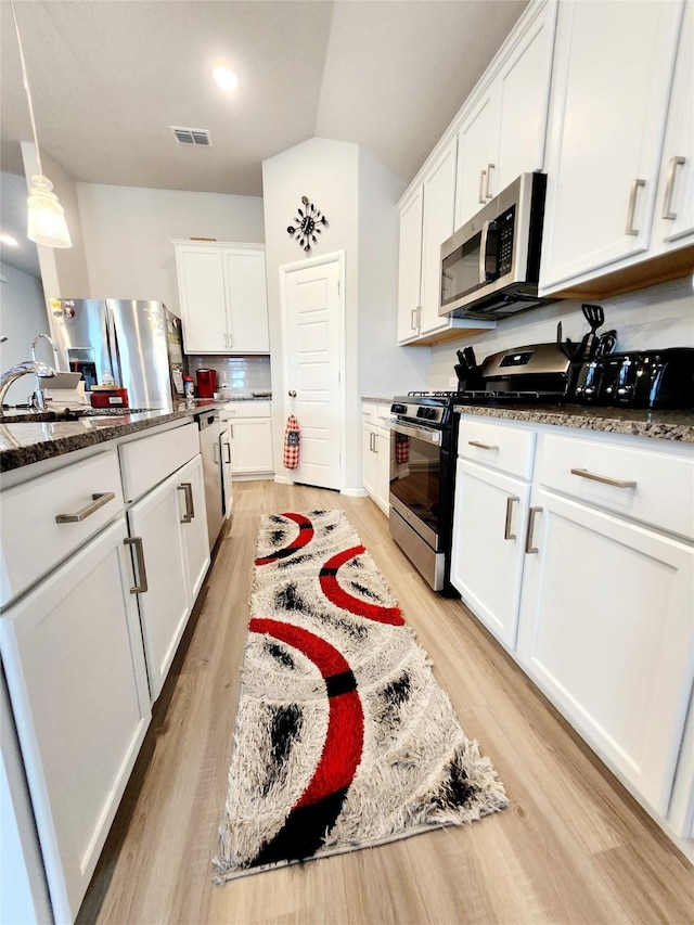 kitchen featuring decorative light fixtures, light hardwood / wood-style flooring, stainless steel appliances, and white cabinets