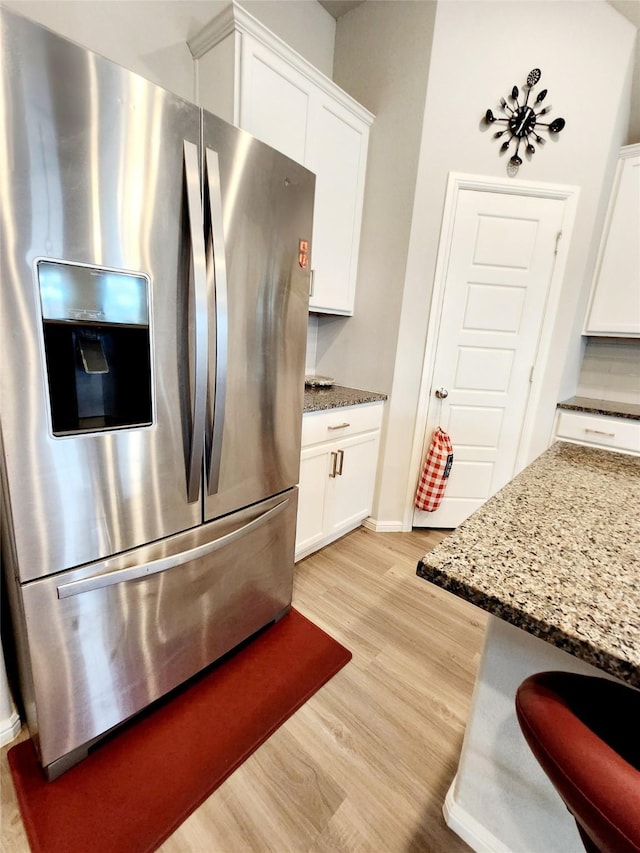 kitchen with stone countertops, light hardwood / wood-style floors, white cabinets, and stainless steel refrigerator with ice dispenser