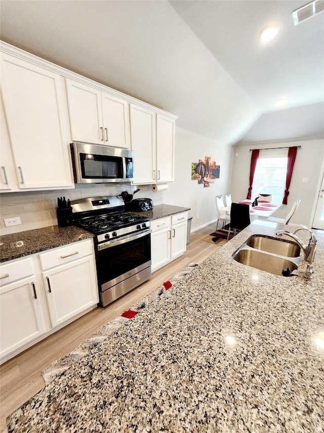 kitchen with stainless steel appliances, dark stone countertops, and white cabinets