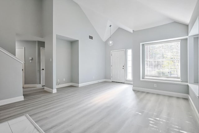 foyer with high vaulted ceiling and light wood-type flooring