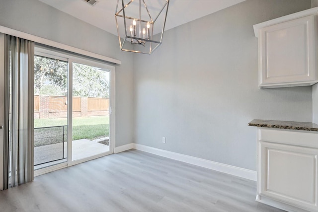 unfurnished dining area featuring light wood-type flooring and a chandelier