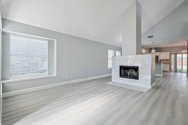 unfurnished living room with lofted ceiling, a fireplace, and light hardwood / wood-style floors