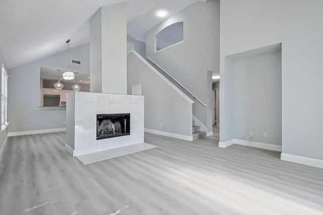 unfurnished living room featuring high vaulted ceiling, a fireplace, and light hardwood / wood-style floors