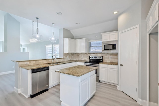 kitchen with stainless steel appliances, white cabinetry, a kitchen island, and sink