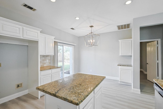 kitchen featuring white cabinetry, a kitchen island, pendant lighting, and light stone counters